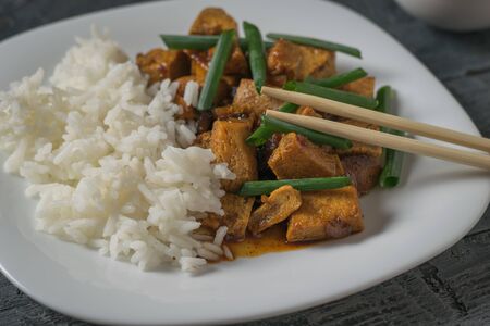 Chopsticks in a plate of rice and fried tofu cheese. Vegetarian Asian dish.の写真素材