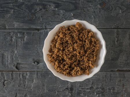 White bowl of quinoa porridge on a wooden table. Flat lay. Healthy diet.