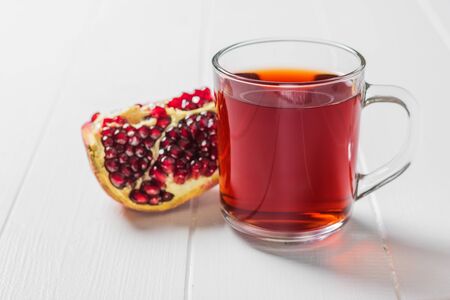 A mug of pomegranate juice and a ripe pomegranate on a white table. Drink useful for health.の写真素材