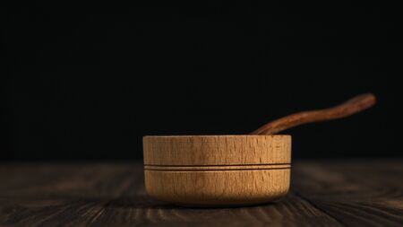 Wooden spoon and wooden Cup on a dark wooden table. Set of rustic dishes on the table.の写真素材