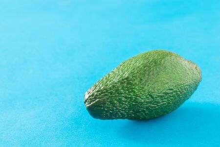 Large fruit of ripe avocado on a blue background. Delicious tropical vegetable.の写真素材