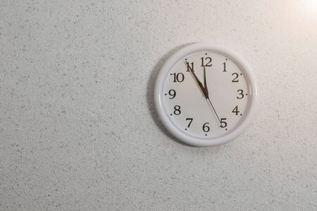 Analog clock with hands on the wall with textured plaster. Device for determining the time.