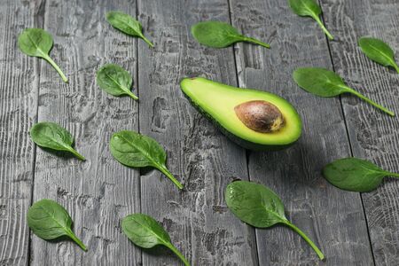 Scattered spinach leaves and half an avocado on a black wooden table. Ingredients for the drink and salad.の写真素材
