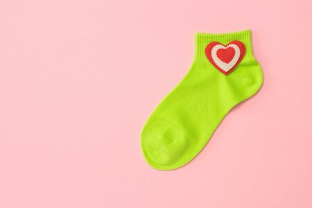 Green sports socks with a red heart on a pink background. The concept of sport and love. Flat lay.