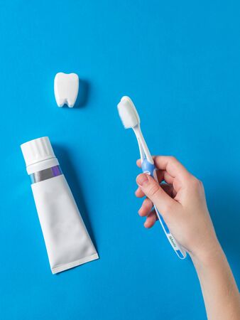 A child is holding a toothbrush on a blue table with toothpaste. Means to care for the oral cavity.の写真素材