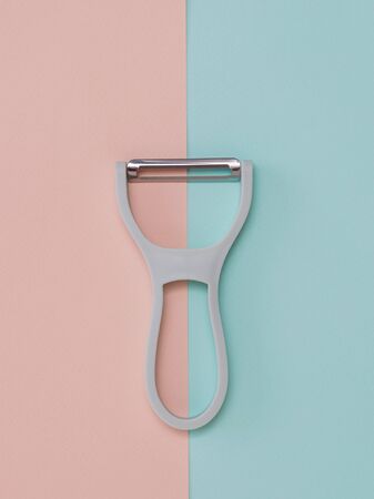 A gray peeler with a plastic handle on a two-color background. Kitchen appliances.の写真素材