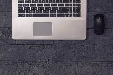 Laptop with a wireless mouse on a wooden background. The concept of workplace organization....