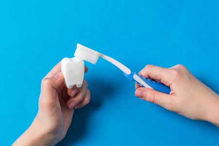 The child cleans the tooth figurine with a blue toothbrush with silicone bristles. Means to care for the oral cavity.の写真素材
