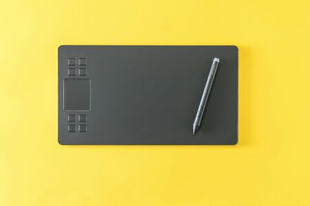 Graphic tablet with a pencil on a bright yellow background. A modern device for working with image...