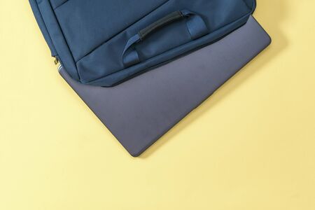 Laptop sticking out of a blue bag on a yellow background. Accessories for study, business and work.の写真素材