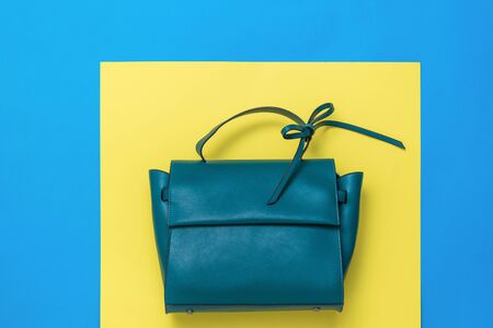 Leather women's bag in turquoise color on a yellow and blue background. The view from the top. Flat lay.の写真素材