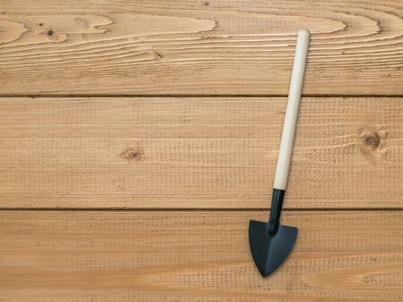A shovel with a wooden handle on a background of wooden boards. A tool for cultivating the soil. A set of garden tools.の写真素材