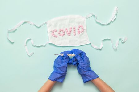 Hands in medical gloves with a thermometer and a medical mask on a light background. Prevention of the spread of coronavirus.の写真素材