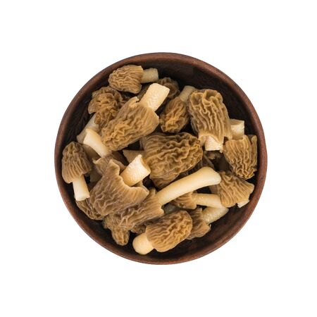 Clay bowl with fresh morels isolated on a white background. The first spring mushrooms.