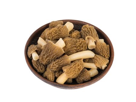 A small clay bowl with morels isolated on a white background. The first spring mushrooms.の写真素材