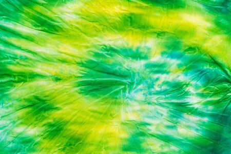 Yellow-green fabric in tie dye style. White clothes painted by hand. Flat lay. Place for text.の写真素材