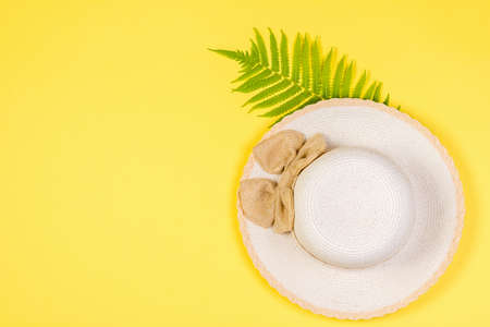A large sun hat with a palm leaf on a yellow background. The view from the top. Concept of recreation on the sea coast.の写真素材