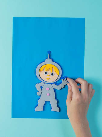 A child creates a paper collage of an astronaut on a blue background. The creativity of paper.の写真素材