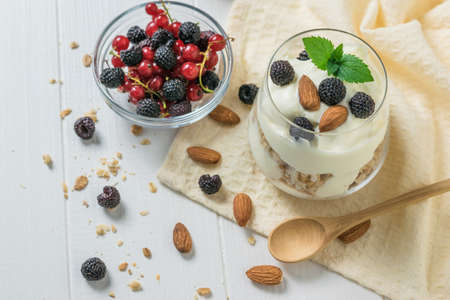 Yogurt with granola and blackberries in a glass Cup on a cloth. Vegetarian food with prebiotics.
