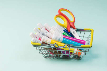 Colored markers and scissors in the basket on a light background. Universal markers for school and office.の写真素材