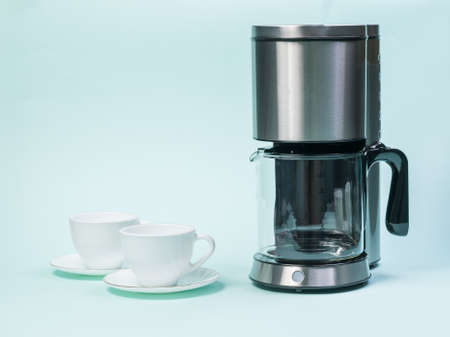 A drip coffee maker and two white cups on a blue background. The concept of a classic Breakfast.の写真素材
