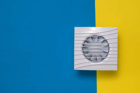 Square fan on a yellow and blue background. Equipment for the removal of dirty air.