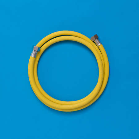 Yellow gas hose coiled on a blue background. Organization of natural gas supply.の写真素材