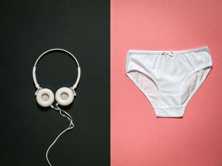 White headphones and white panties on a red and black background. Underwear. The view from the top. Beautiful lingerie. Flat lay.の写真素材