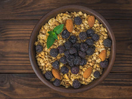 Black raspberries, mint, oatmeal and almonds in a clay bowl on the table. The dish is rich in fiber.の写真素材