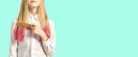 A girl combs her dyed hair on a light background. Fashionable hair color.の写真素材