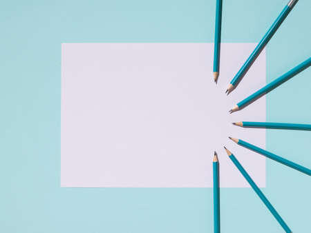Graphite pencils and a white sheet of paper on a blue background. Paper and office supplies.の写真素材