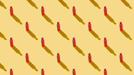 Background of red plastic bottles on a yellow background. Cosmetic product in a plastic bottle. Seamless.の写真素材