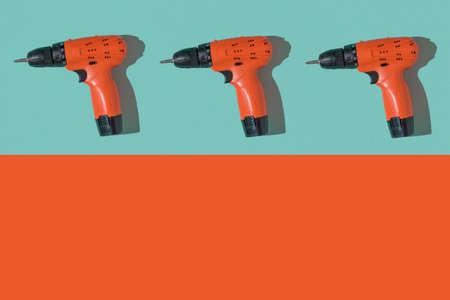 Three orange screwdrivers on a blue and orange background. A tool with a battery.