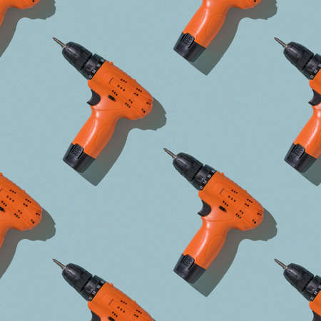 Seamless pattern of orange screwdrivers on a blue background. A tool with a battery.の写真素材