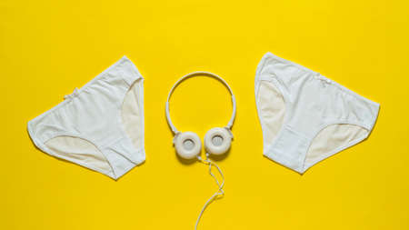 Two panties and headphones on a yellow background. Underwear. The view from the top. Beautiful lingerie. Flat lay.の写真素材