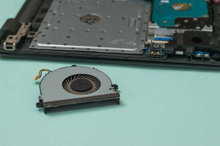 Cooling fan lying next to the laptop being repaired. Repair and restore laptop performance.の写真素材