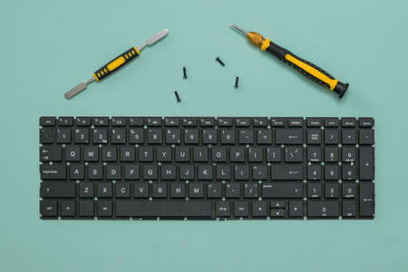Laptop keyboard and screwdrivers with screws on a blue background. Repair and restore laptop...