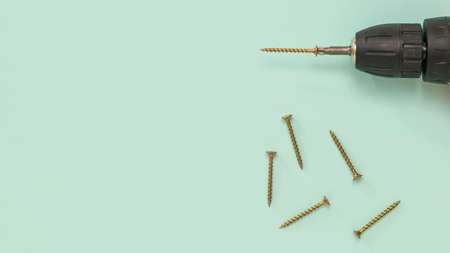 A screwdriver with a bat and yellow metal screws on a blue background. A tool with a battery.の写真素材