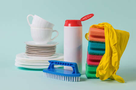 Dishes and detergents on a light blue background. The concept of cleaning and maintaining cleanliness.の写真素材