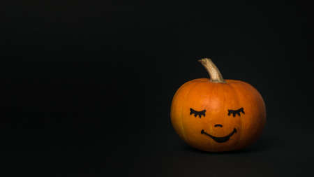 Pumpkin with a painted face on a black background. Halloween party.の写真素材