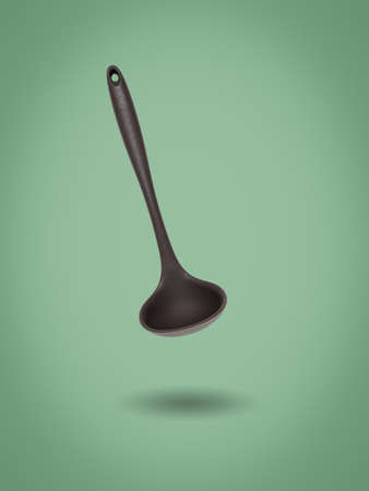 Kitchen silicone ladle on a green background. The concept of cooking.の写真素材