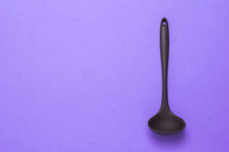 Brown silicone ladle on a lilac background. Modern Cutlery.の写真素材