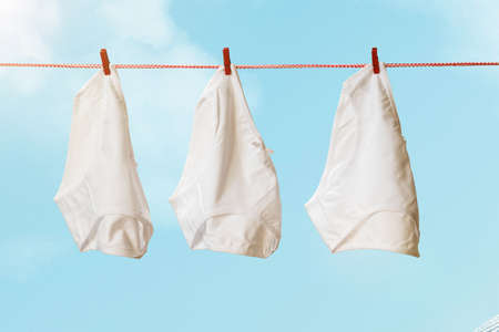 Three white women's panties on a clothesline against a blue sky. Drying women's underwear.の写真素材