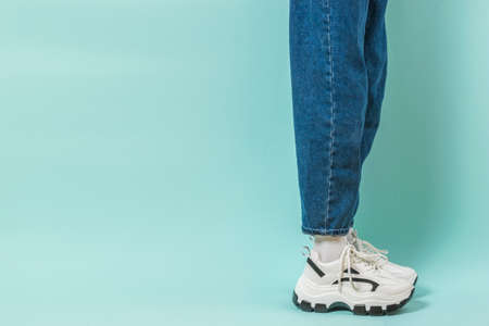 A side view of the leg of the girl in wide jeans and sneakers on a high sole. Stylish youth clothing...