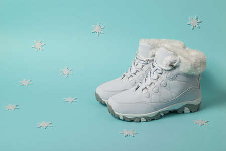 White insulated women's winter sneakers on a blue background with snowflakes. Sports shoes for winter.の写真素材