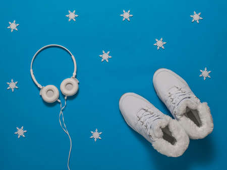 White insulated women's winter sneakers on a blue background with snowflakes. Sports shoes for winter.の写真素材