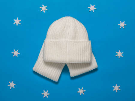 Warm knitted hat and scarf on a blue background with snowflakes. Fashionable winter accessories.の写真素材