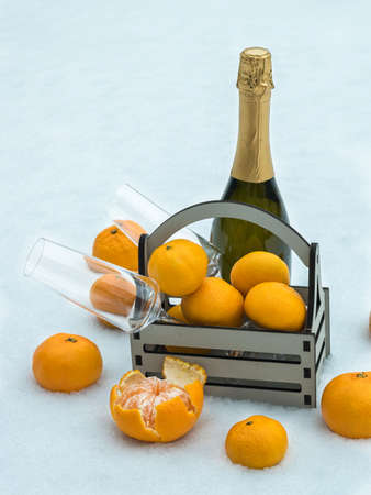 A bottle of champagne, a box of tangerines and glasses in the snow. Christmas treat.の写真素材