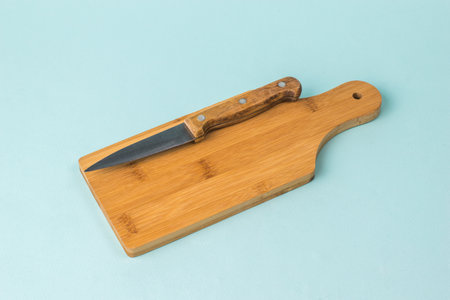 Cutting board with a knife on a light blue background. Kitchen accessories.の写真素材