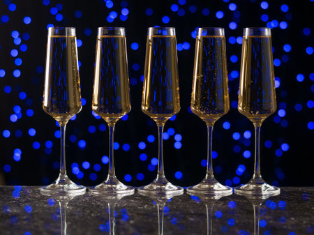 Five glasses of wine standing neatly on the table against a blue bokeh background. A popular alcoholic drink.の写真素材
